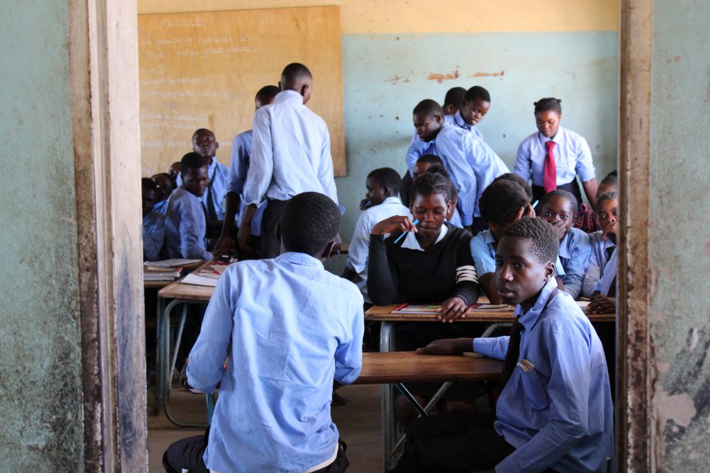Students gathered in a Zambian classroom wearing uniforms and participating in education.