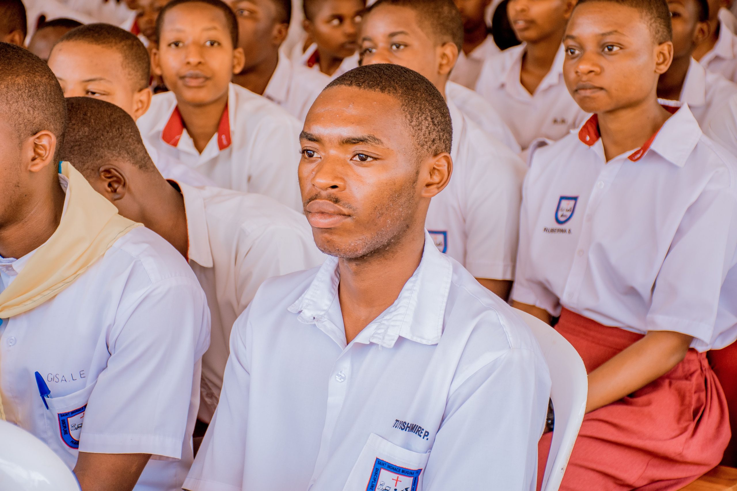 Home A group of students attending a lecture wearing school uniforms, focused and attentive.